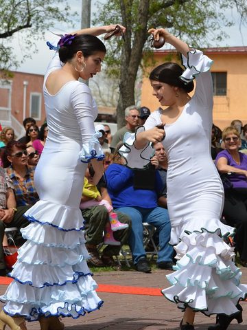 Two flamenco dancers in long white dresses, with their arms up