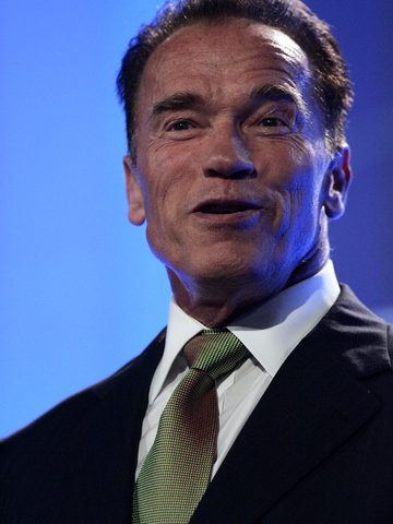 Arnold Schwarzenegger in a dark suit and a green tie