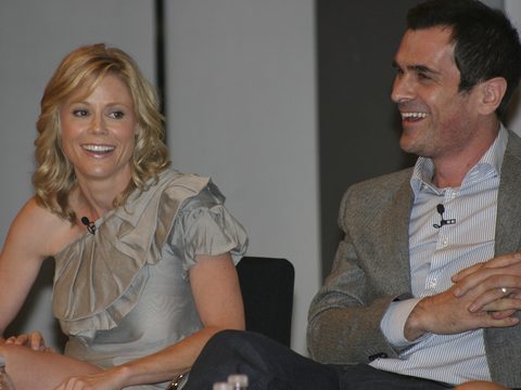 Actors Julie Bowen and Ty Burrell laughing on a stage