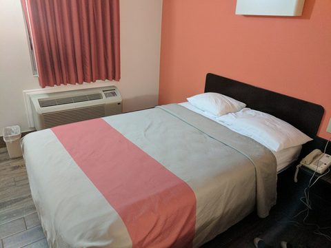 A hotel room with a double bed and an air conditioner under the window
