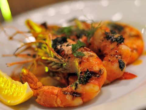 Grilled prawns with herbs and a piece of lemon on a white plate