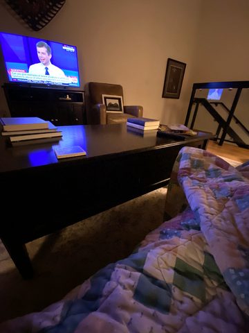 A TV on in a dark living room, seen from the couch under a blanket