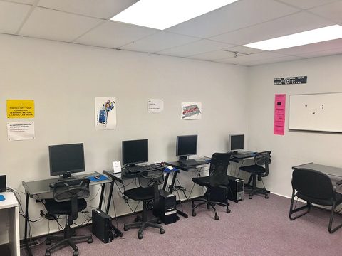 A small computer room with four computers on desks
