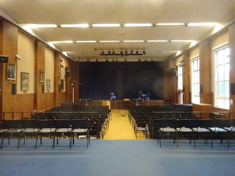 A big school hall with rows of chairs and a stage
