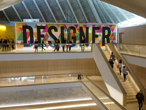 Inside the Design Museum in London: wooden stairs, visitors and a big colorful sign