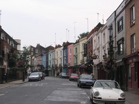 Portobello Road in London: a street with pink, blue and white houses and parked cars