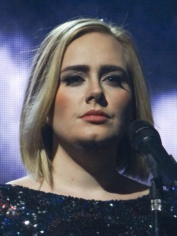 Adele singing on stage, next to a microphone