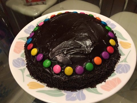 A homemade chocolate cake with colorful candies around the top