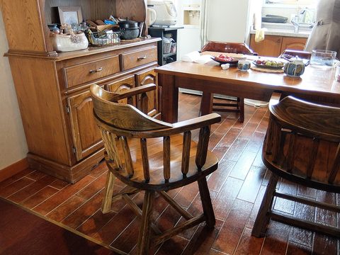 A kitchen with a wooden table, chairs and a cupboard