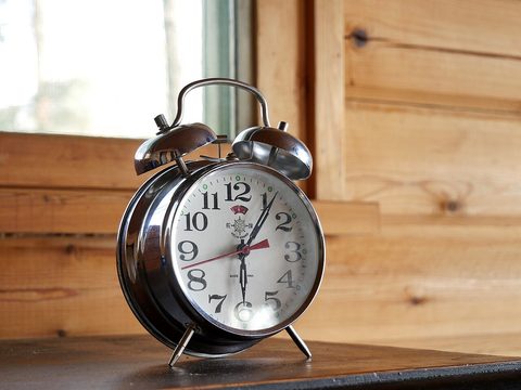 An old silver alarm clock with two bells on a wooden table